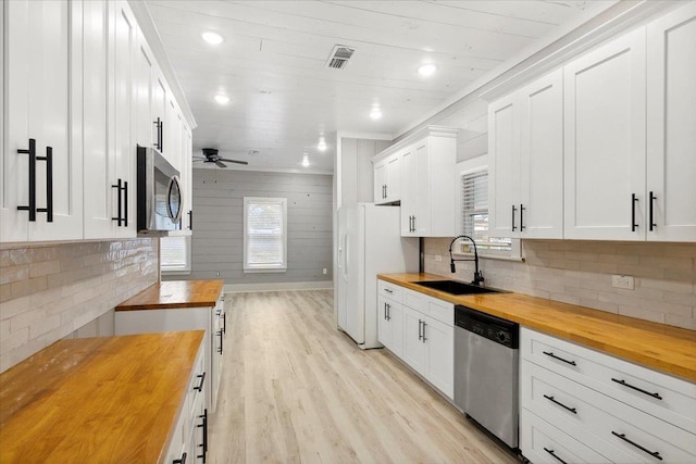 kitchen featuring stainless steel appliances, white cabinetry, and wooden counters