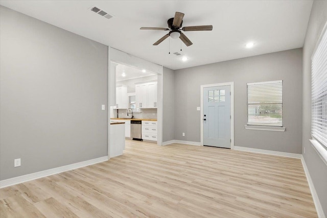 unfurnished living room with ceiling fan, light hardwood / wood-style floors, and sink