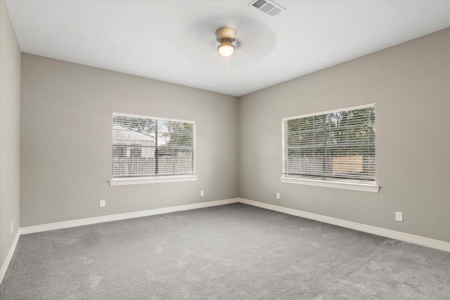 carpeted spare room featuring plenty of natural light and ceiling fan