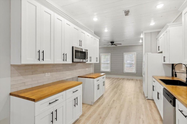 kitchen with white cabinets, appliances with stainless steel finishes, butcher block countertops, and sink