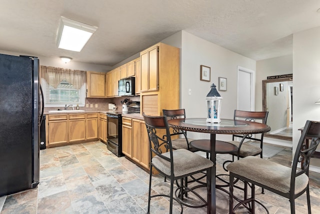 970 Evergreen Ln, Beaumont, TX 77706 - kitchen with black appliances, light stone finish floors, a sink, light brown cabinetry, and light countertops