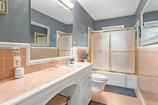 970 Evergreen Ln, Beaumont, TX 77706 - bathroom with tile walls, toilet, shower / bath combination with glass door, vanity, and tile patterned flooring