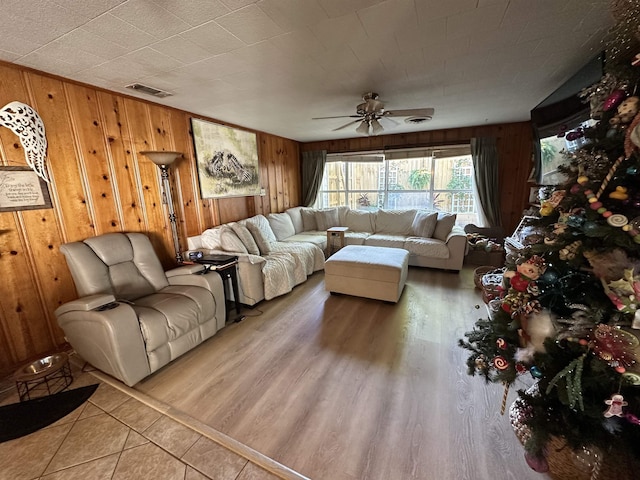 living room featuring ceiling fan and wooden walls