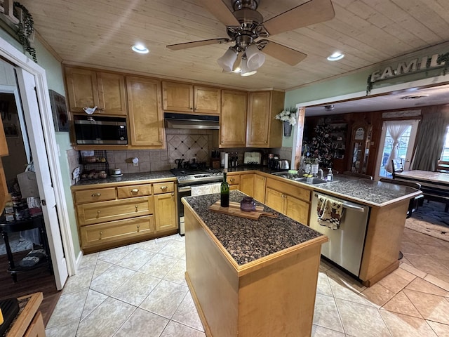 kitchen featuring ceiling fan, decorative backsplash, a kitchen island, and appliances with stainless steel finishes