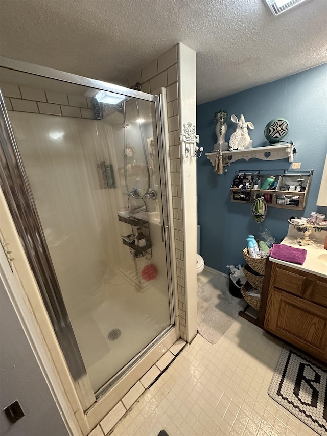 bathroom featuring vanity, a shower with shower door, a textured ceiling, and toilet