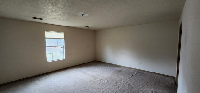 carpeted empty room featuring a textured ceiling