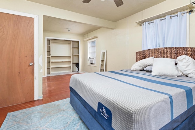 bedroom with a closet, hardwood / wood-style flooring, ceiling fan, and cooling unit