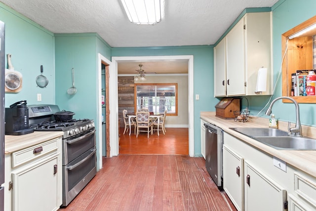 kitchen with white cabinets, sink, ceiling fan, appliances with stainless steel finishes, and light hardwood / wood-style floors