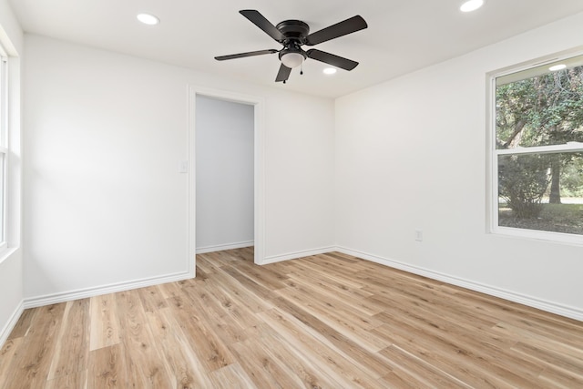 spare room with light hardwood / wood-style floors, a wealth of natural light, and ceiling fan