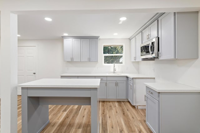 kitchen featuring light wood-type flooring, gray cabinetry, and sink