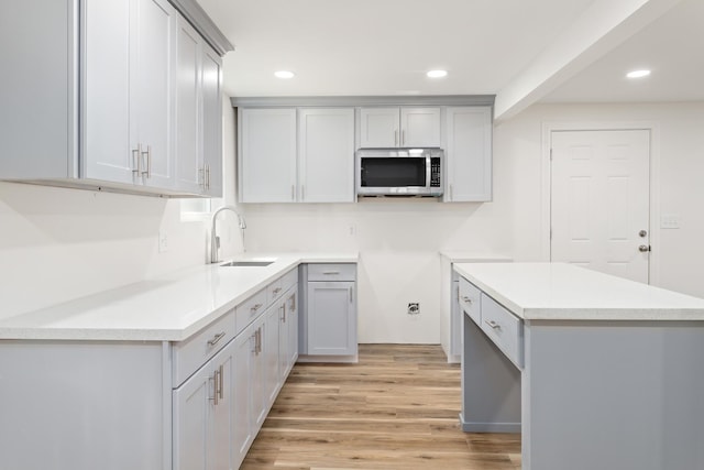 kitchen with gray cabinetry, sink, and light wood-type flooring