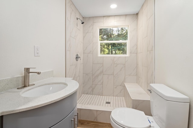 bathroom with tiled shower, vanity, and toilet