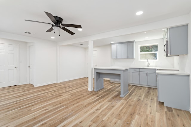 kitchen with light hardwood / wood-style floors, ceiling fan, gray cabinetry, and sink