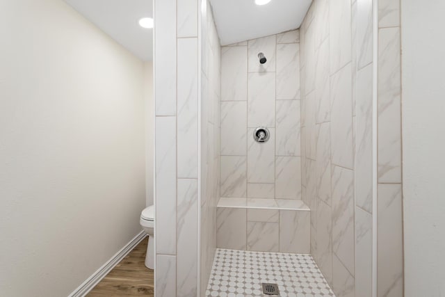 bathroom featuring a tile shower, hardwood / wood-style flooring, and toilet