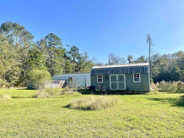 rear view of property featuring a yard and an outdoor structure