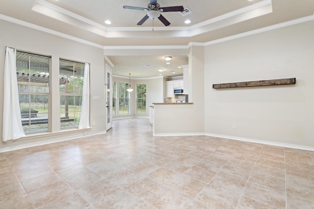 unfurnished living room featuring a tray ceiling, crown molding, and ceiling fan