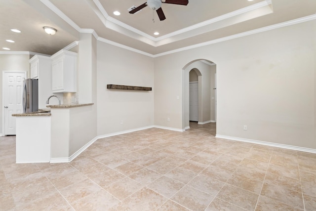 spare room with sink, ceiling fan, a raised ceiling, and crown molding