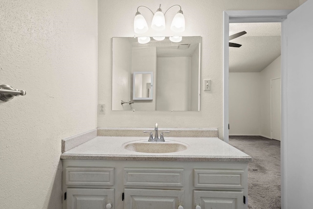 bathroom featuring a textured wall, a ceiling fan, and vanity