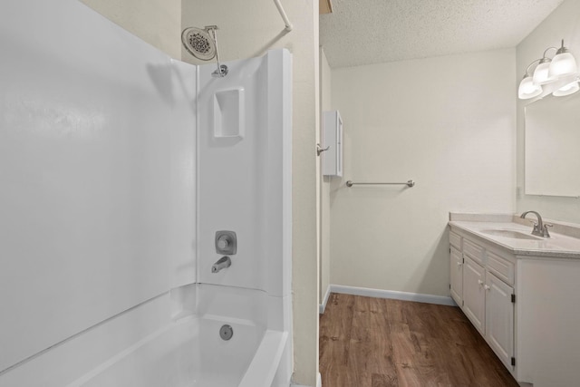 bathroom with wood finished floors, a textured ceiling, vanity,  shower combination, and baseboards