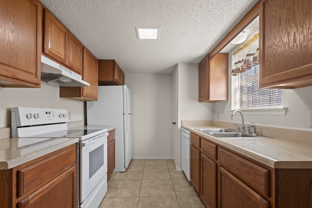 kitchen with under cabinet range hood, light countertops, a sink, white appliances, and brown cabinetry