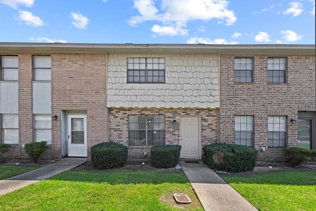 townhome / multi-family property with a front lawn and brick siding