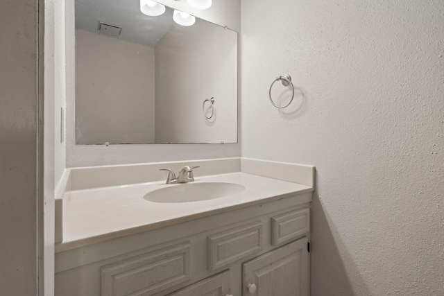 bathroom with a textured wall and vanity