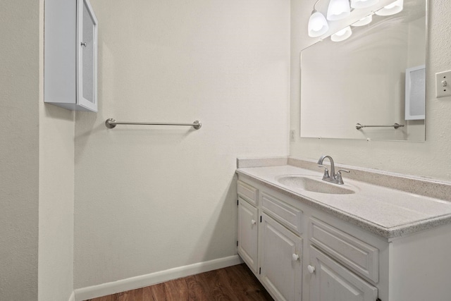 bathroom with baseboards, wood finished floors, and vanity