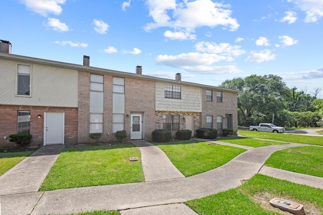 multi unit property featuring a front lawn and brick siding