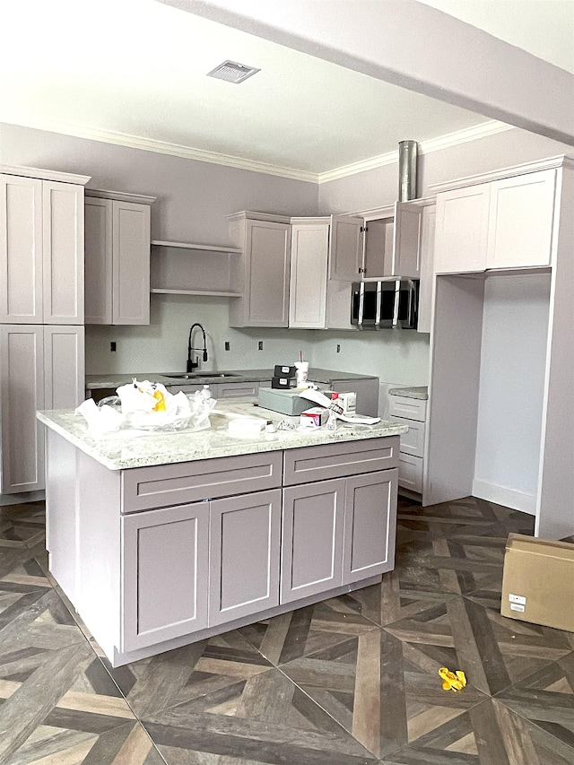 kitchen with ornamental molding, a sink, light stone counters, and gray cabinetry