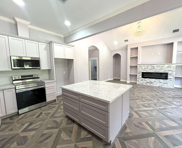10675 Vinson St, Beaumont, TX 77713 - kitchen featuring stainless steel appliances, arched walkways, crown molding, light stone counters, and backsplash