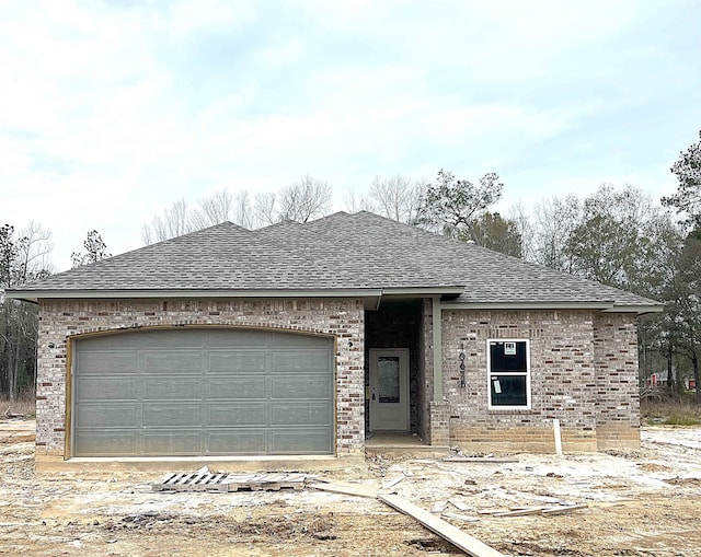 view of front facade featuring an attached garage, brick siding, and roof with shingles