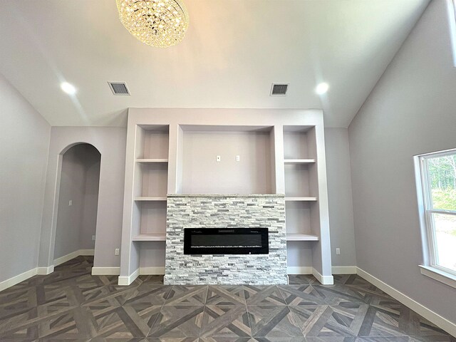 10675 Vinson St, Beaumont, TX 77713 - unfurnished living room with baseboards, built in shelves, a stone fireplace, vaulted ceiling, and arched walkways