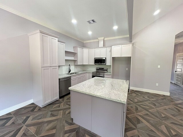 10675 Vinson St, Beaumont, TX 77713 - kitchen with appliances with stainless steel finishes, ornamental molding, a center island, baseboards, and light stone counters