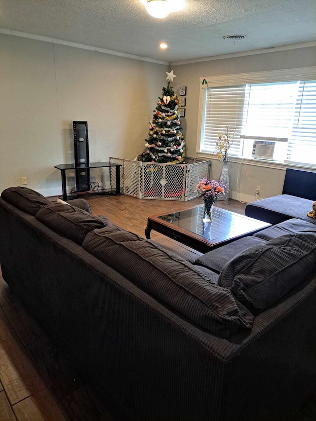 living room featuring crown molding, wood-type flooring, and a textured ceiling