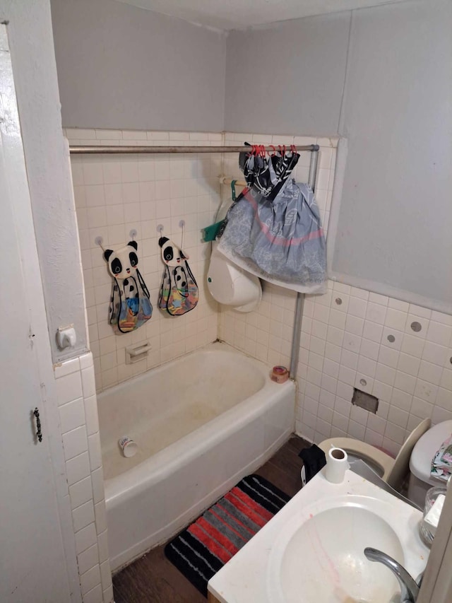 bathroom with a bathing tub, sink, toilet, tile walls, and hardwood / wood-style flooring