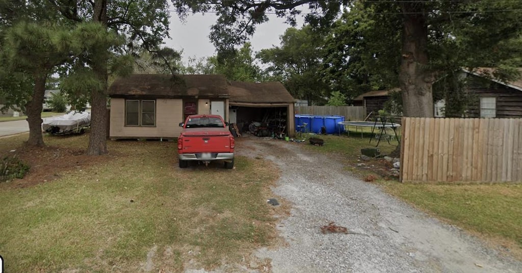 ranch-style home featuring a garage, a trampoline, and a front lawn