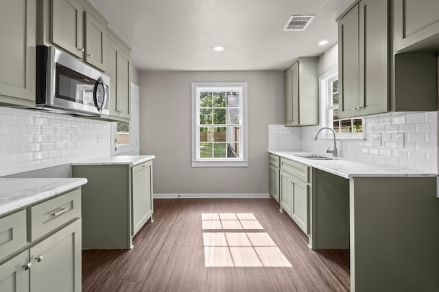 815 Central Dr, Beaumont, TX 77706 - kitchen featuring stainless steel microwave, a sink, decorative backsplash, dark wood-style flooring, and baseboards