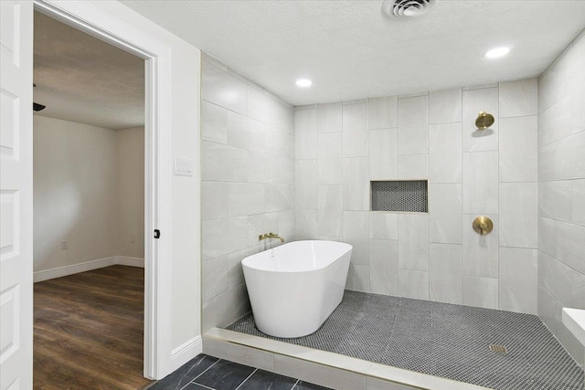 bathroom with tile patterned floors, tile walls, separate shower and tub, and a textured ceiling