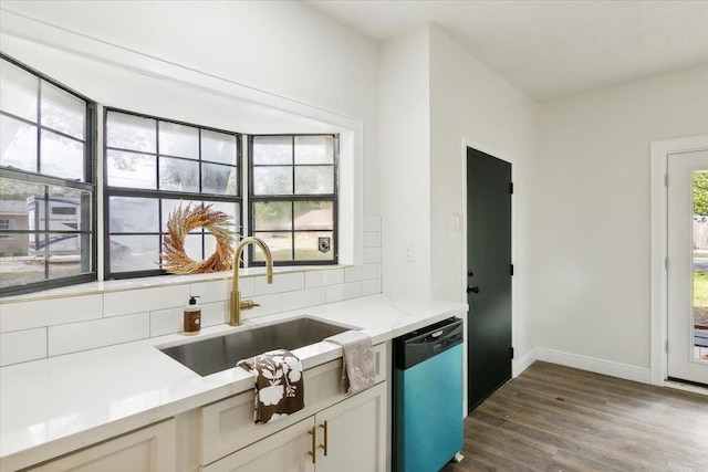 kitchen featuring dishwasher, sink, dark wood-type flooring, light stone counters, and backsplash