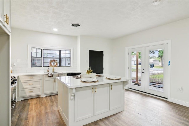 kitchen featuring sink, french doors, backsplash, white cabinets, and light wood-type flooring