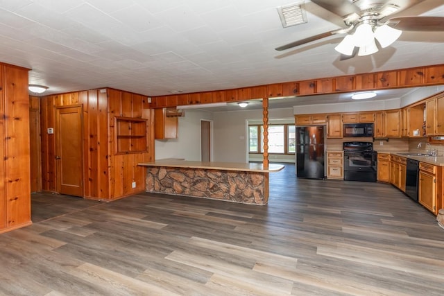 3012 Berry Ave, Groves, TX 77619 - kitchen with black appliances, wood finished floors, brown cabinets, light countertops, and wood walls