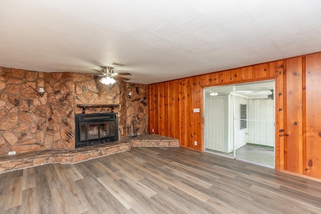 3012 Berry Ave, Groves, TX 77619 - unfurnished living room featuring ceiling fan, wood finished floors, wood walls, and a stone fireplace
