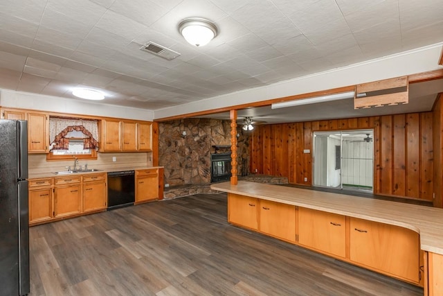 3012 Berry Ave, Groves, TX 77619 - kitchen featuring black appliances, light countertops, a stone fireplace, dark wood-style floors, and wooden walls
