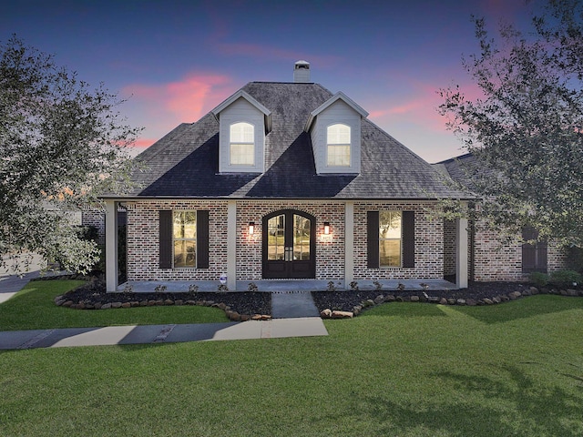 view of front of home featuring a lawn, french doors, and brick siding