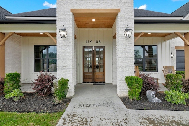 view of exterior entry with covered porch and french doors