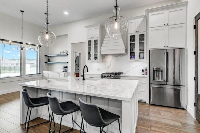 kitchen featuring a large island, high quality appliances, white cabinetry, and backsplash