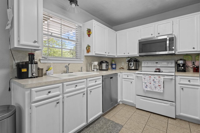 10393 Duncan Rd, Beaumont, TX 77713 - kitchen with appliances with stainless steel finishes, white cabinetry, light countertops, and light tile patterned floors