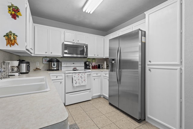 10393 Duncan Rd, Beaumont, TX 77713 - kitchen featuring stainless steel appliances, white cabinets, light countertops, and light tile patterned flooring