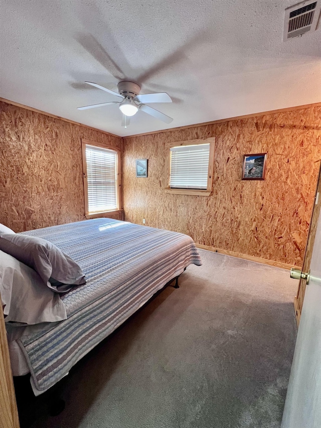 carpeted bedroom featuring a textured ceiling, ceiling fan, and visible vents