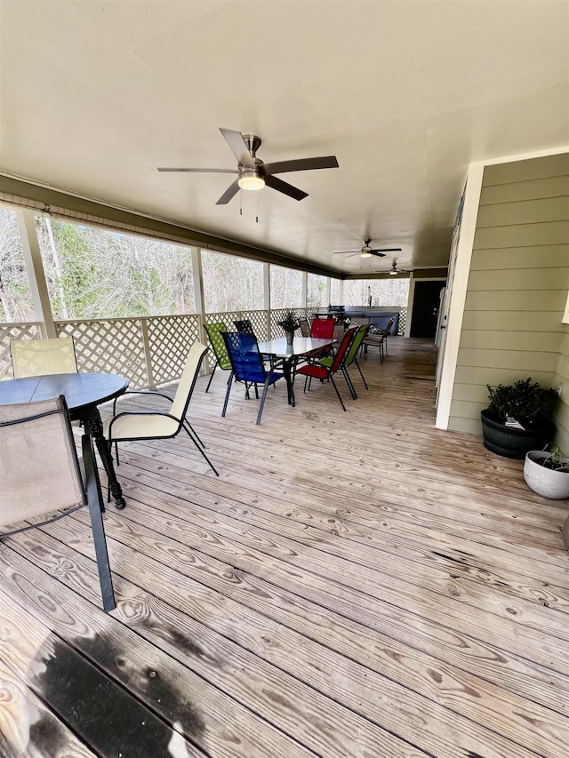 wooden terrace with outdoor dining area and a ceiling fan